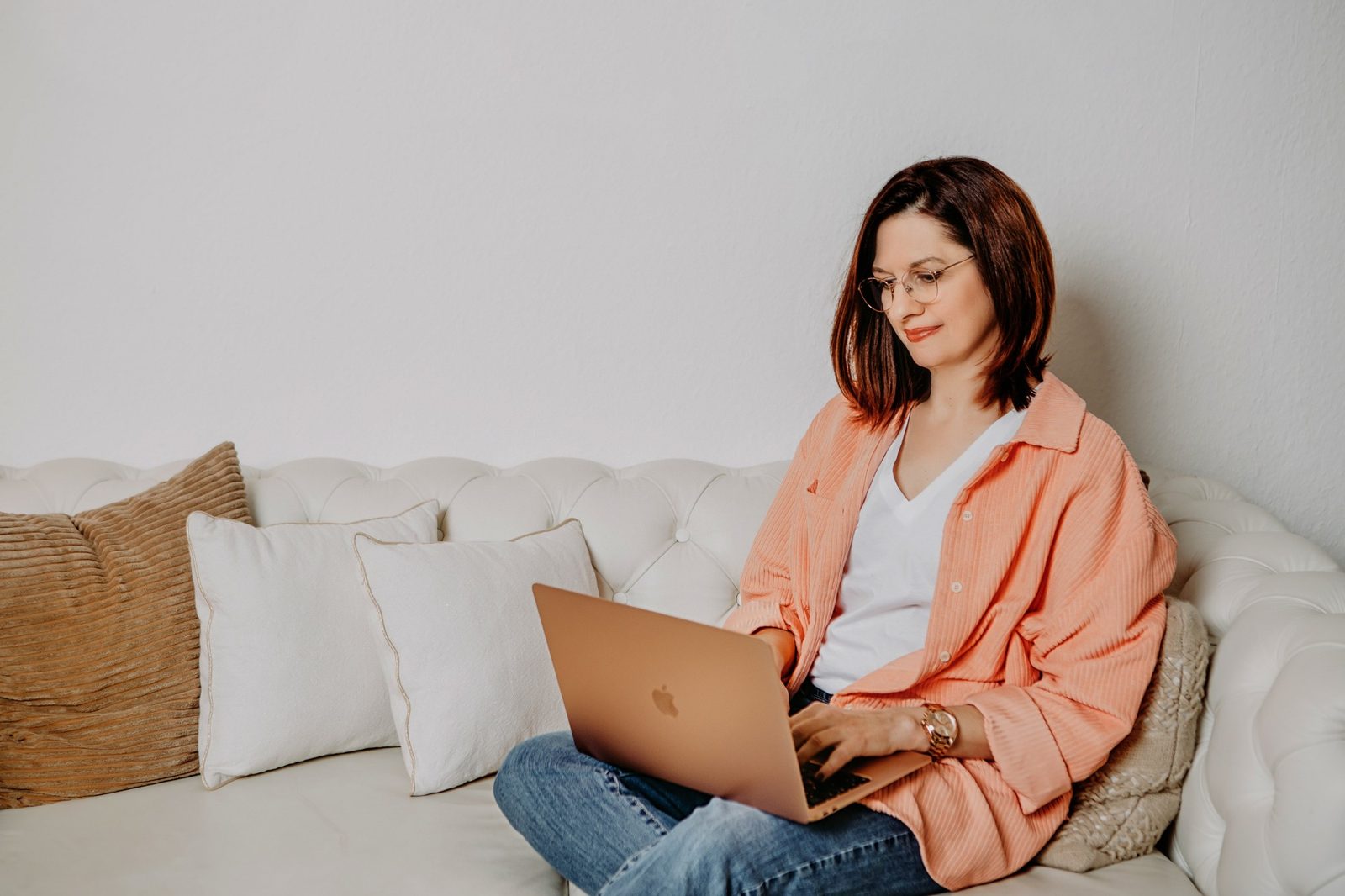 Bettina Höld arbeitet am Laptop auf einem hellen Sofa