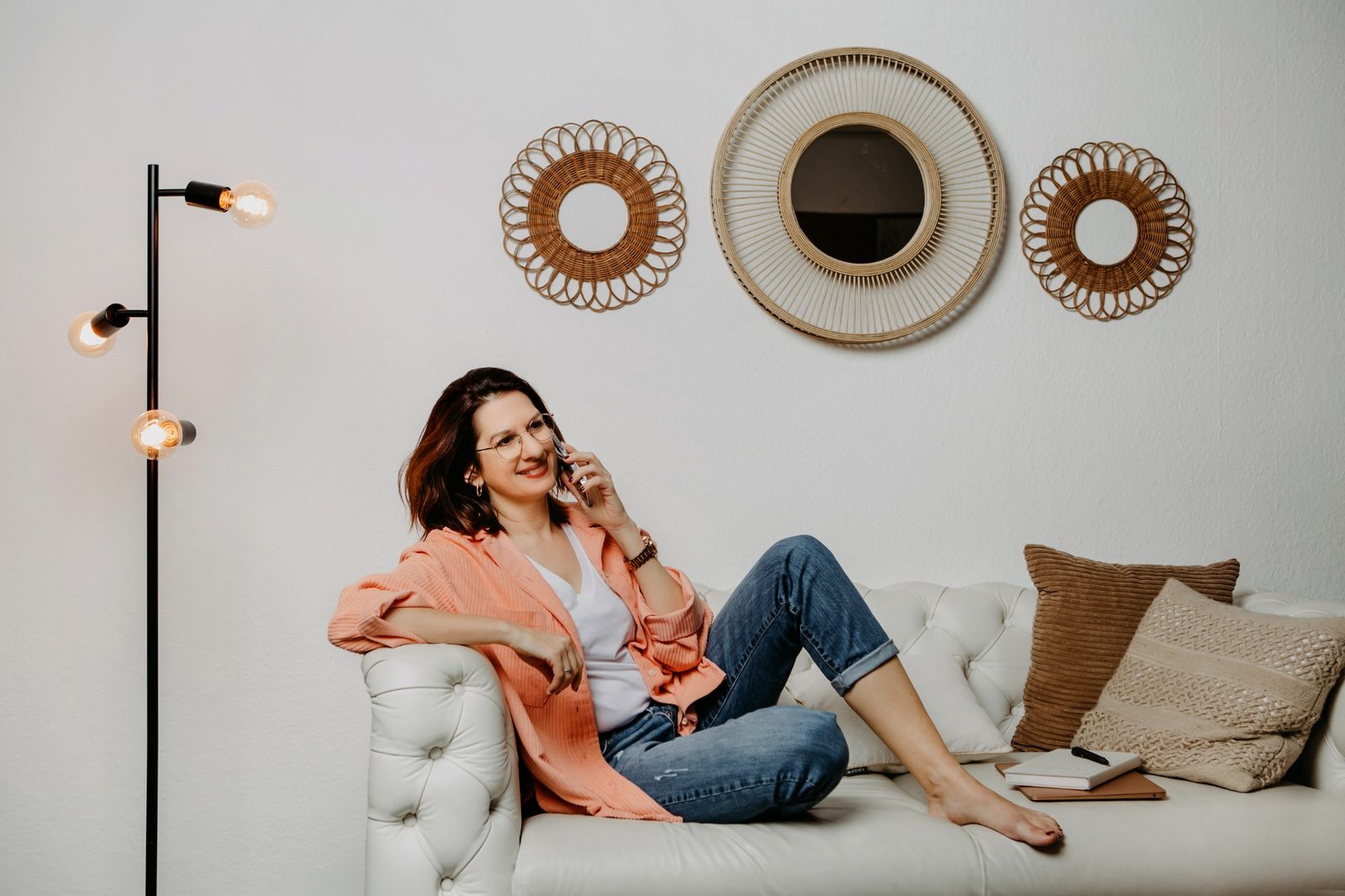 Bettina Höld entspannt auf einem hellen Sofa beim Telefonat